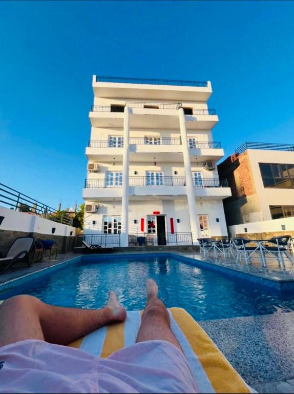 a person laying on a raft in a swimming pool in front of a building at Happiness Guest House in Luxor