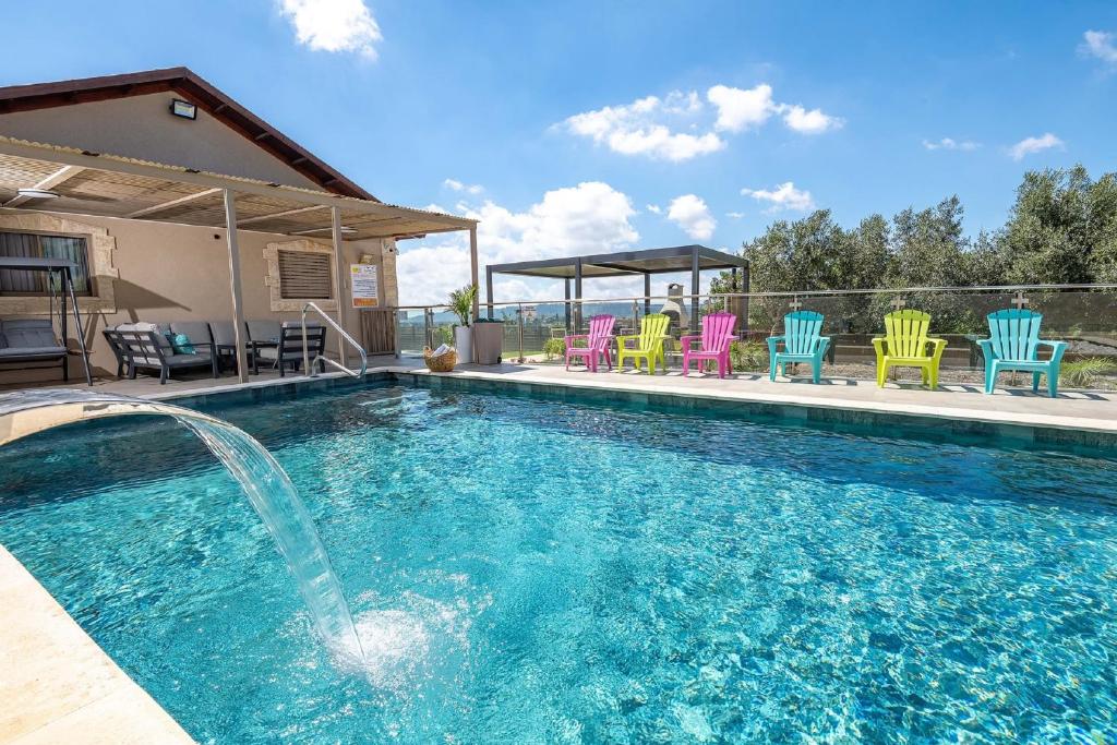 a swimming pool with chairs and a fountain at Villa Glory in Even Menahem