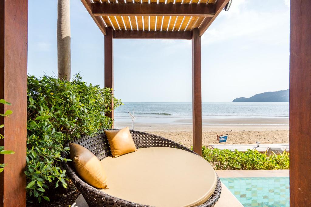 a table and chairs with the beach in the background at Cozy Beachfront Samroiyod in Baanphakrimlay 