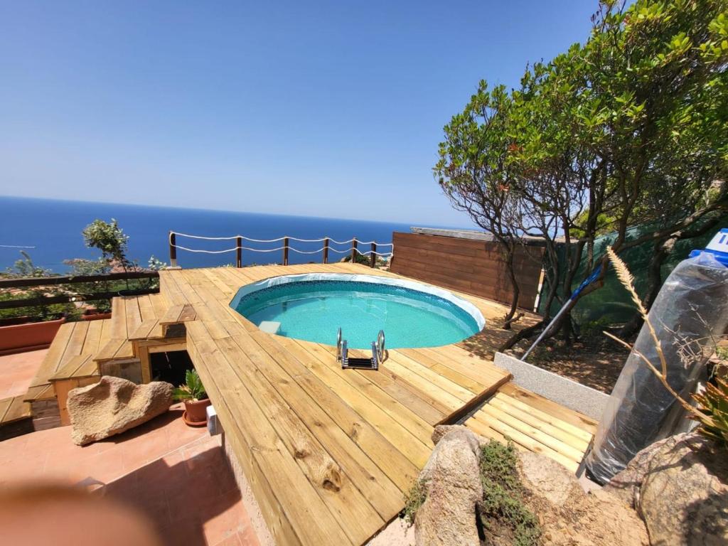 a swimming pool on a wooden deck next to the ocean at Villa Sunny Side - Panoramic View in Costa Paradiso