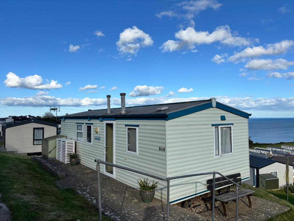 a white house with a bench in front of it at Beer Head Caravan Park B68 in Seaton