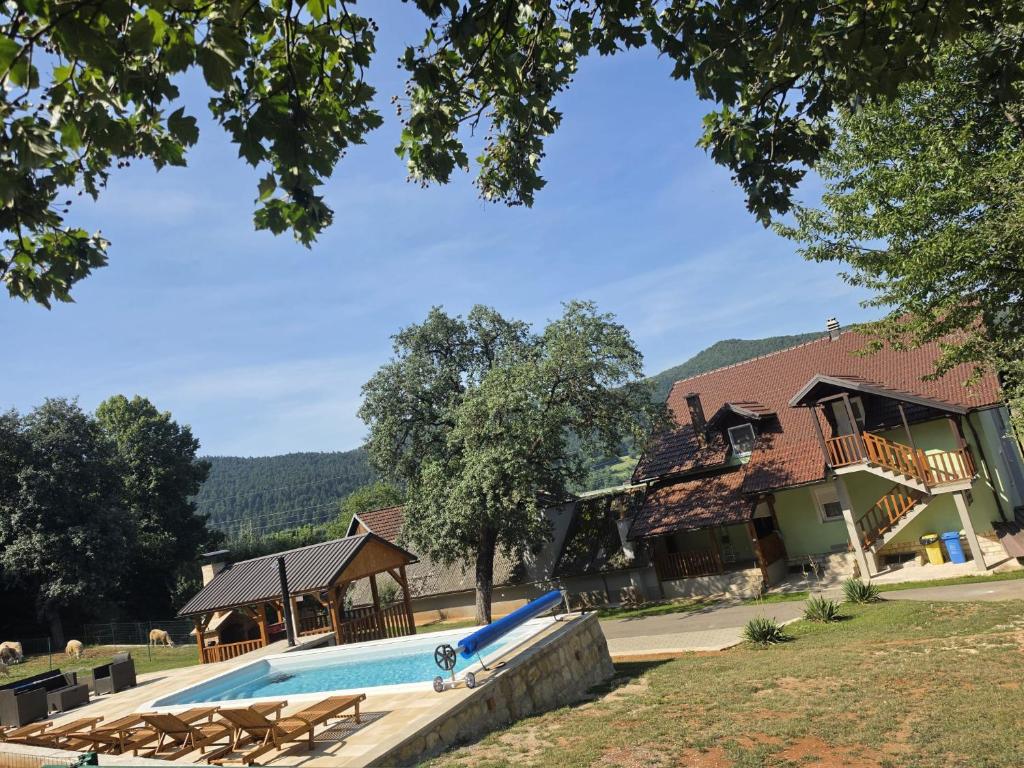 a swimming pool in front of a building with a house at Apartman Silvija in Otočac