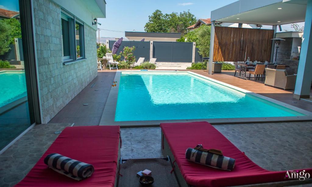 a swimming pool with two chaise lounges next to a house at Villa Vie Luxury Retreat in Blagaj