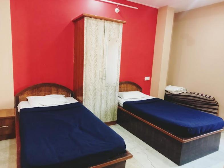 two beds in a room with a red wall at Sri Sapthagiri Comforts in Mysore