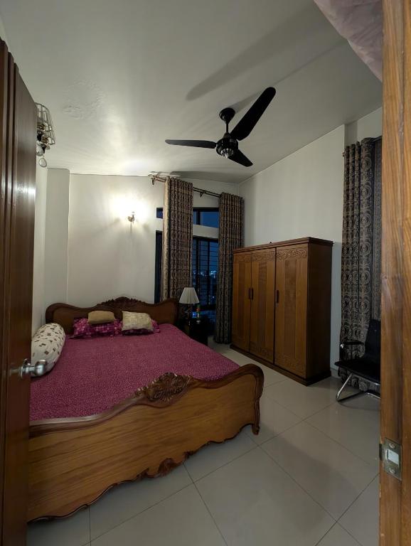 a bedroom with a large wooden bed with purple sheets at Family's penthouse in Dhaka
