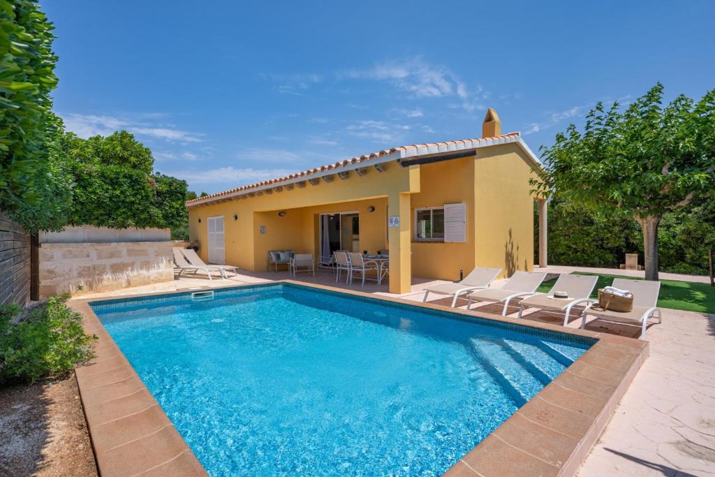 a swimming pool in front of a house at Villa Aries by 3VILLAS in Cala en Forcat