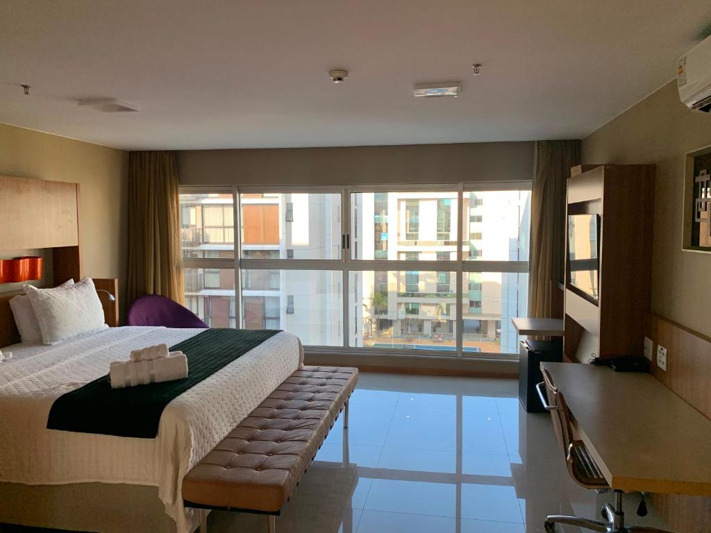a hotel room with a bed and a large window at Flat Sofisticado no Jade Hotel Home Office in Brasília