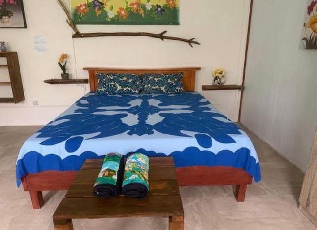 a bedroom with a blue and white bed and a table at Le KAHAIA Rangiroa Tiputa in Rangiroa
