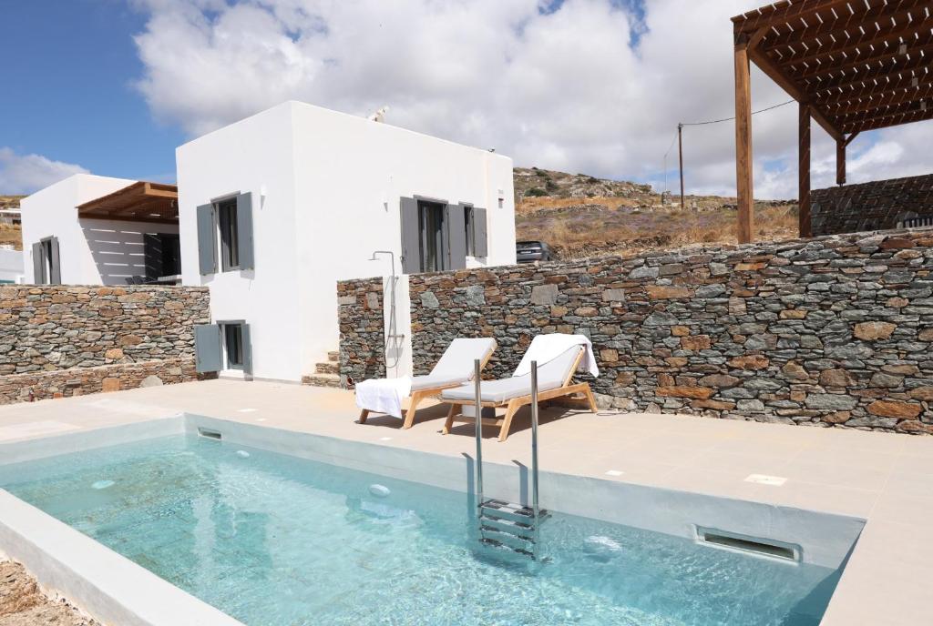 a pool with two chairs and a house at Liotrivi Luxury Residences in Kithnos