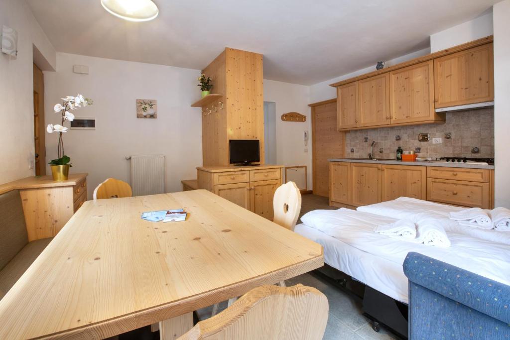 a kitchen with a wooden table and a bed in it at Ciesa Al Drago in Rocca Pietore
