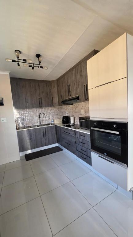 a large kitchen with white tile floors and wooden cabinets at The Manor in Manzini