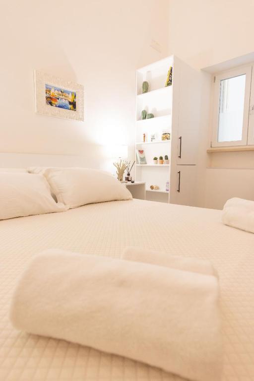 a white bedroom with two beds and a window at Luma Apartment Sperlonga in Sperlonga