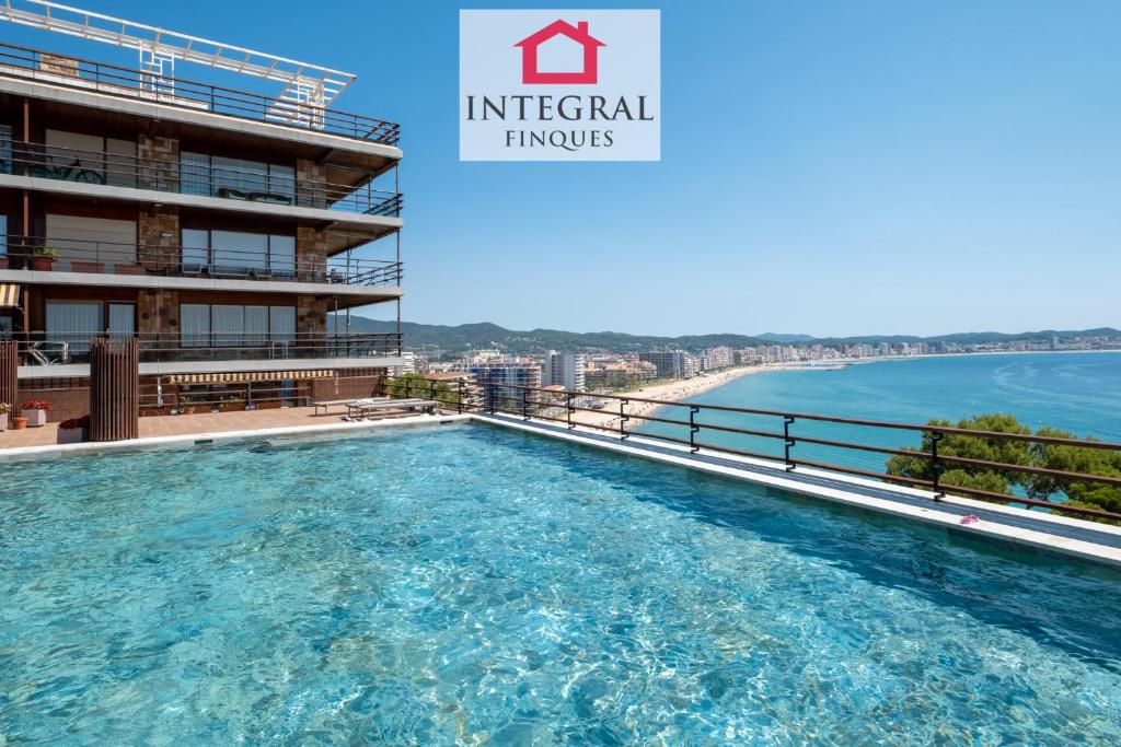 a swimming pool on the roof of a building next to the ocean at Apartament Eden Mar in Platja d'Aro