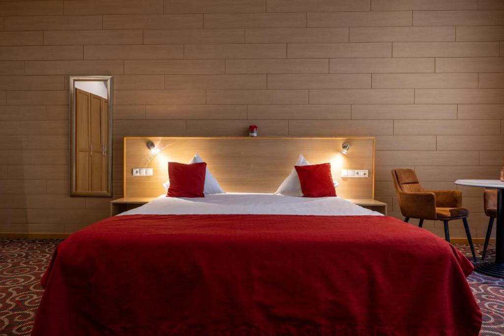 a hotel room with a large bed with red sheets at Hotel INGREDI in Bree
