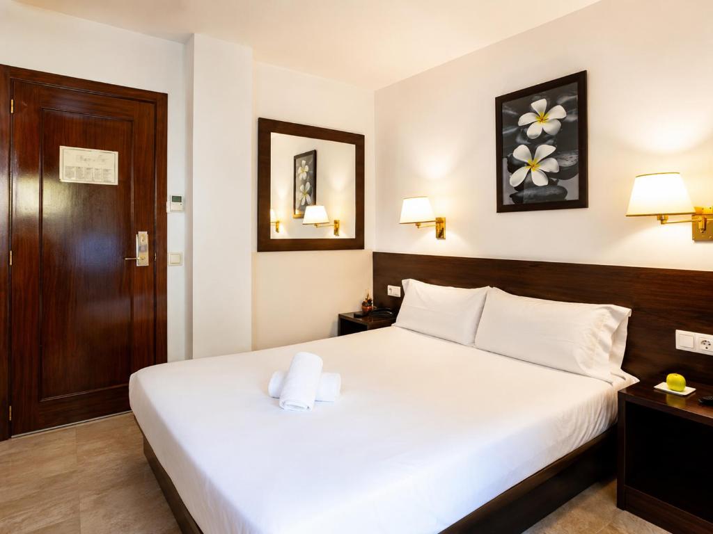 a bedroom with a white bed and a wooden door at Insitu Eurotel Andorra in Andorra la Vella