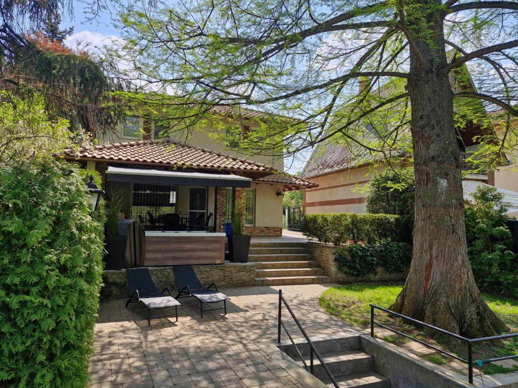 a house with a patio and a tree at Hársfa Jakuzzis Nyaraló Szarvas in Szarvas