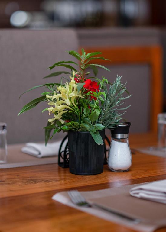 a black vase with flowers on a table at Winsome Hotel Arusha in Themi