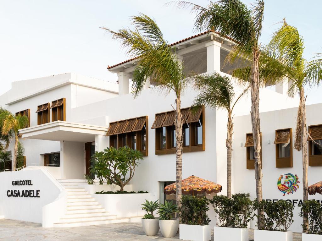 a white building with palm trees in front of it at Grecotel Casa Adele in Platanes