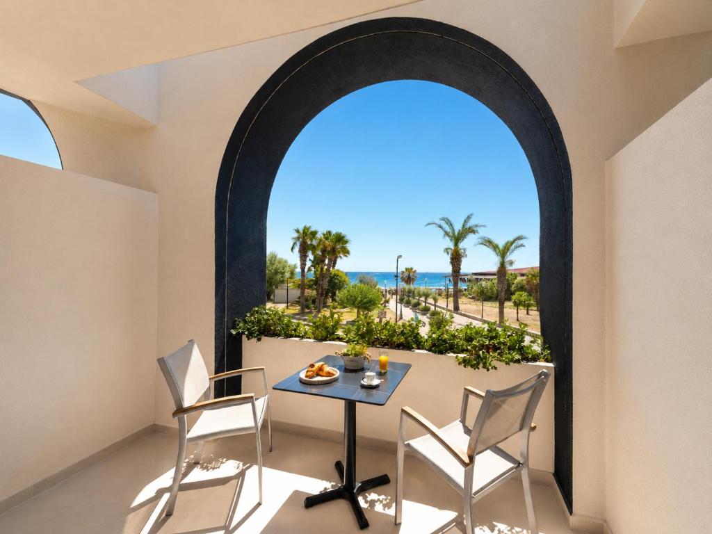 an arched window in a room with a table and chairs at Venezia Sea Side Suites in Faliraki