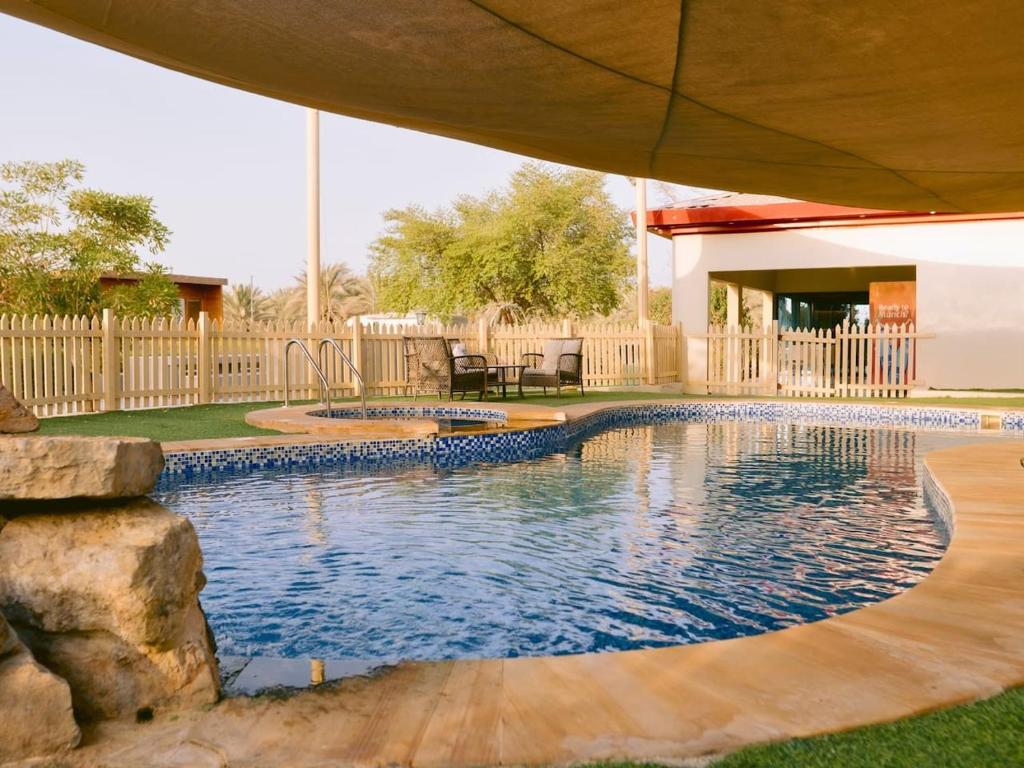 a swimming pool in a yard with an umbrella at Seven Elements Resort in Ras al Khaimah