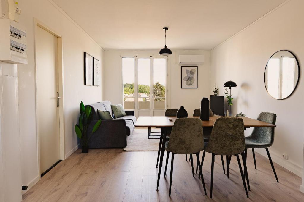 a living room with a table and chairs at Le Traversant - Parking Gratuit in Bourg-lès-Valence