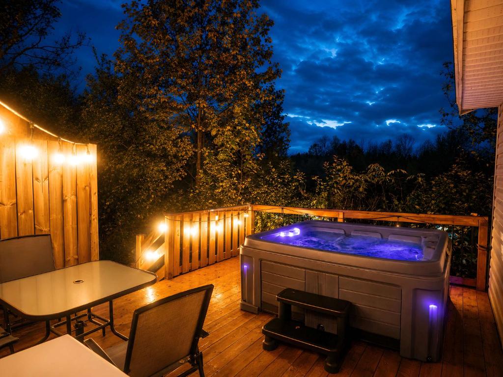 a hot tub on a deck at night at Relaxing Chalet Getaway with Spa Fireplace & BBQ in Saint-Tite-des-Caps