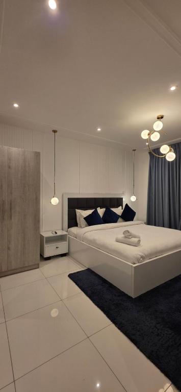 a bedroom with a large white bed with blue pillows at The Loxwood Premier Suites in Accra