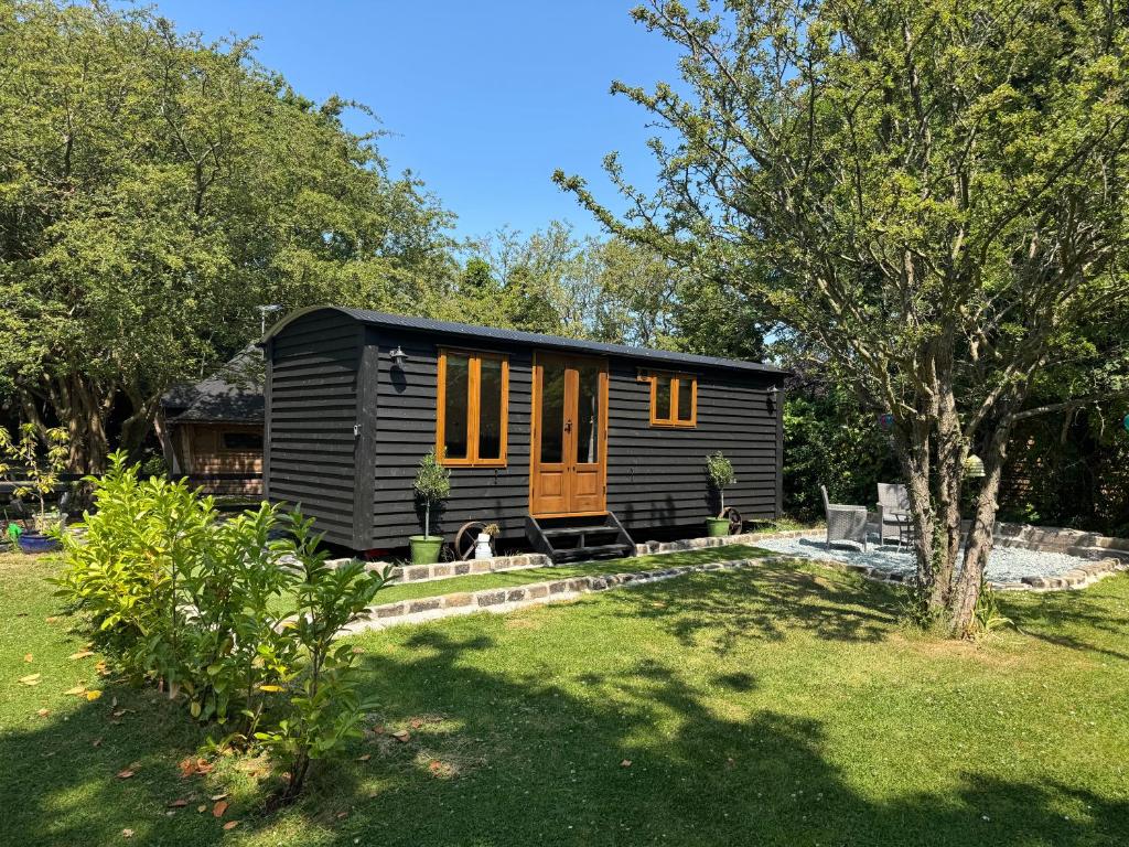 a black tiny house with orange doors in a yard at The Coach House or The Shepherd Hut in Blackpool