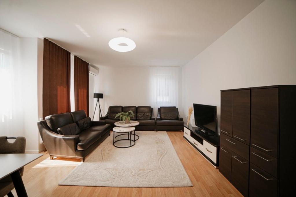 a living room with a couch and a tv at Estilo Apartments in Prishtinë