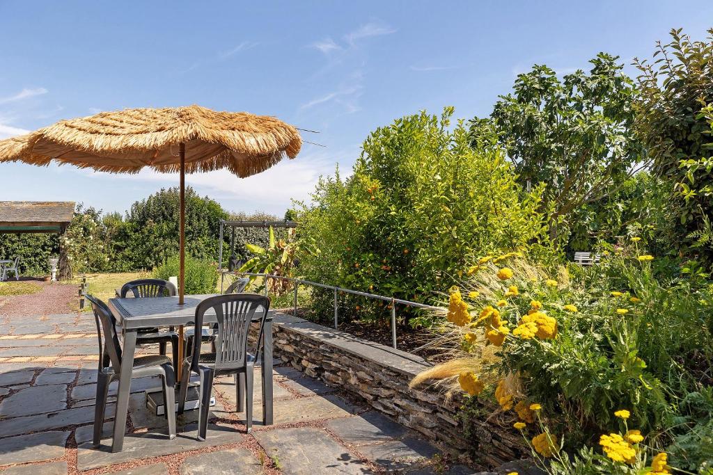 a table and chairs under a straw umbrella at Lorali - Chambre d'Hôtes in Gohier