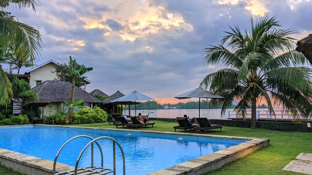 a pool at a resort with people sitting under umbrellas at Cocotinos Manado A Boutique Dive Resort & Spa in Wori