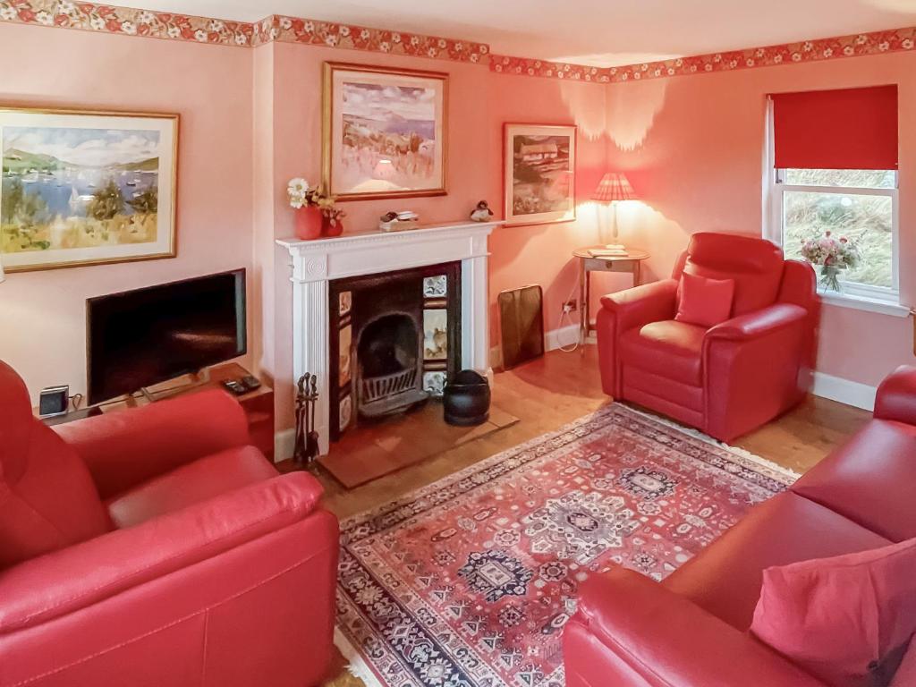 a living room with red chairs and a fireplace at Vindolanda in Fearnmore