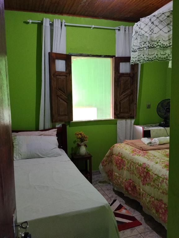 a green bedroom with two beds and a window at Quarto Oliveira in Ibicoara