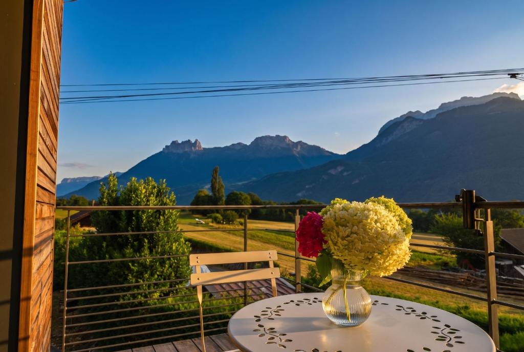 a vase of flowers on a table with a view of mountains at Petit balcon du lac in Lathuile