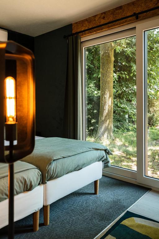 a bedroom with a bed and a large window at Woodboxcabins - Campinggroenpark in Zele