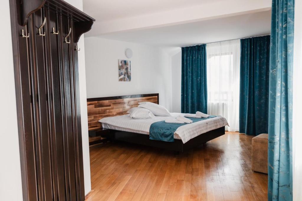 Ein Schlafzimmer mit einem Bett, blauen Vorhängen und Holzboden in der Unterkunft Abigarrado in Rucăr