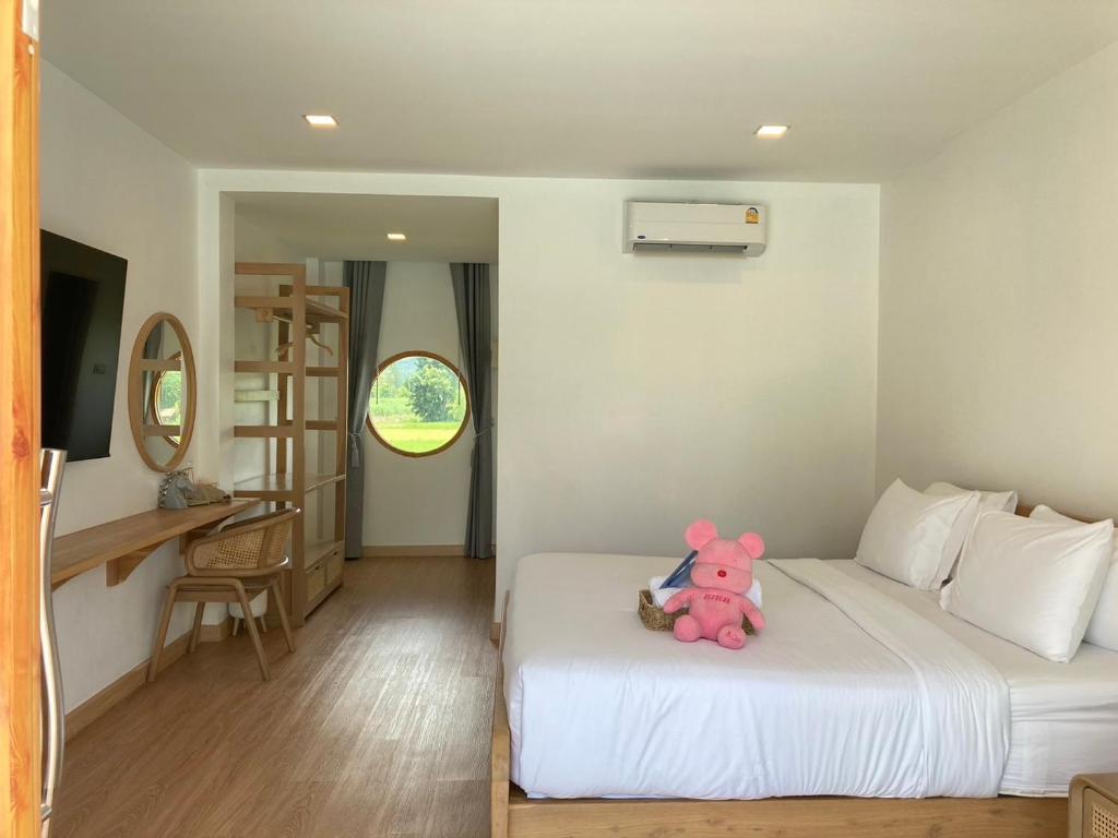 a pink teddy bear sitting on a bed in a room at Monanza Hotel in Ban Thung Prong