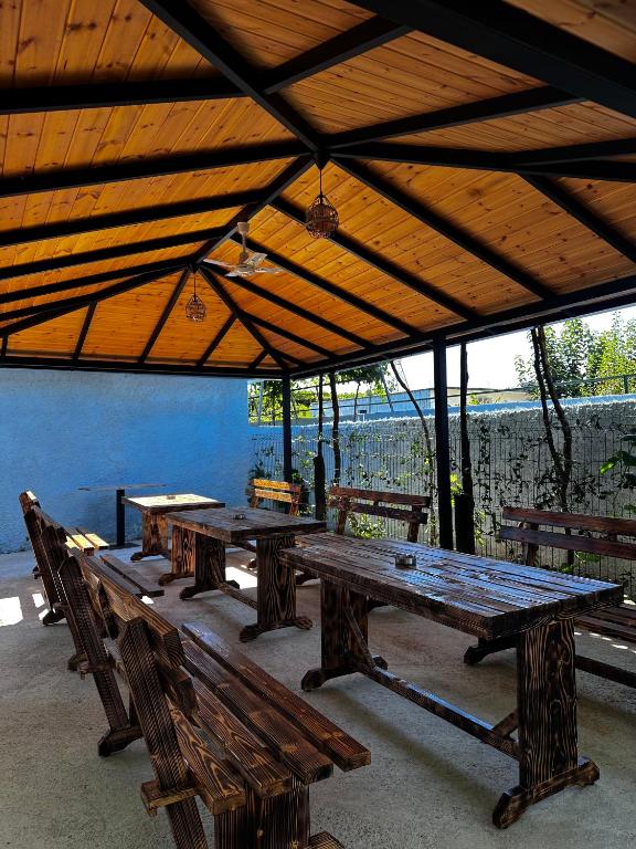 a group of wooden picnic tables under a roof at Family Nest in Shtoji i Ri