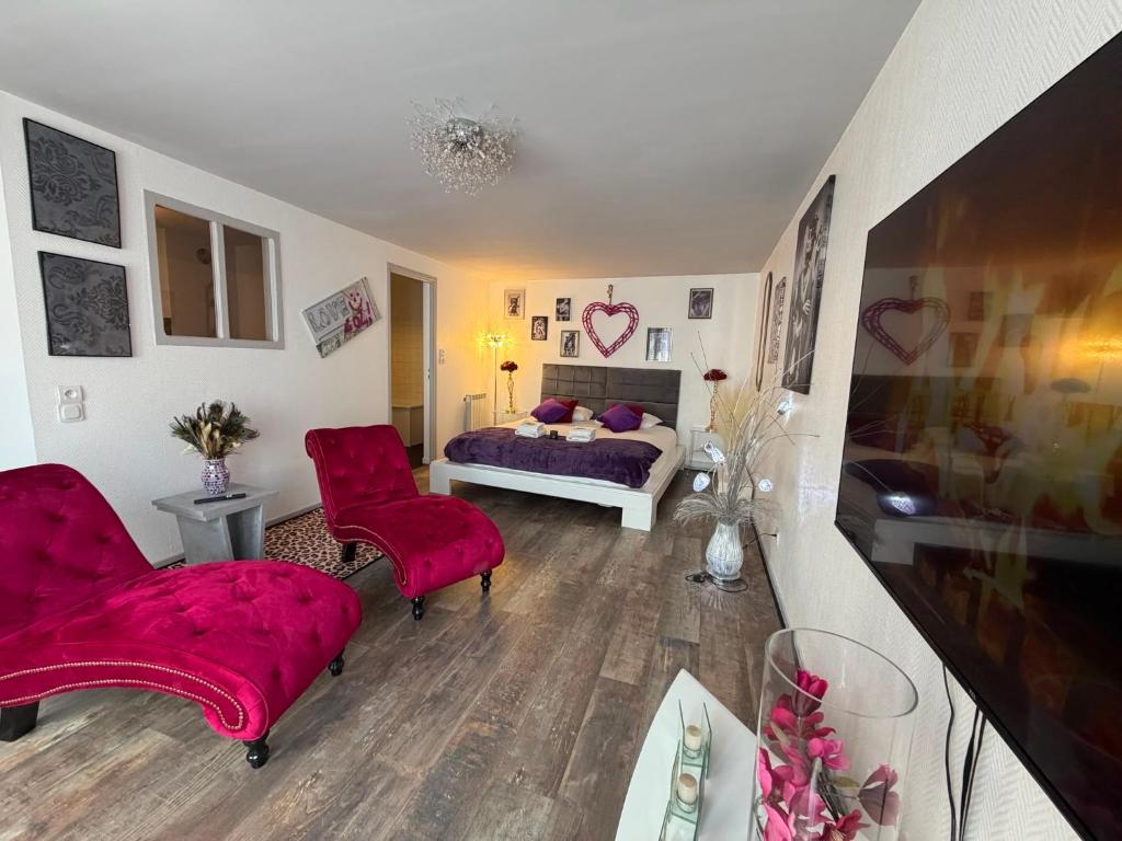 a bedroom with a bed and two red chairs at So Chic Romance au pied du Château in Sedan