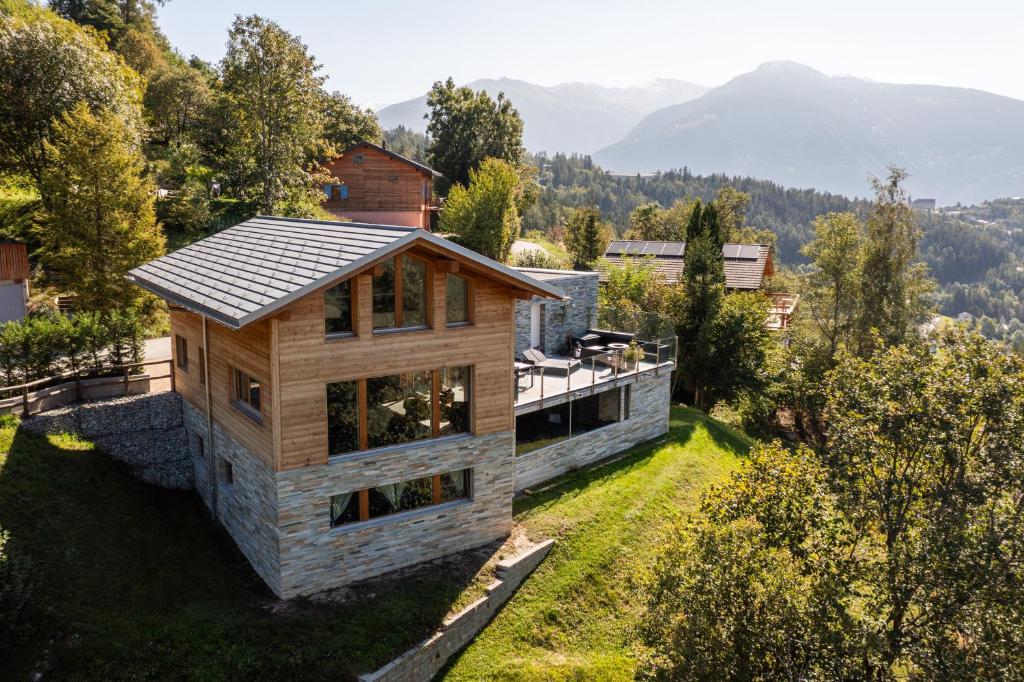 a house on a hill with mountains in the background at Villa moderne avec Jacuzzi - ski - golf in Icogne