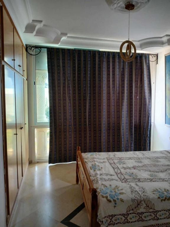 a bedroom with a bed and a large window at Appartement S2 Hammamet Centre in Hammamet