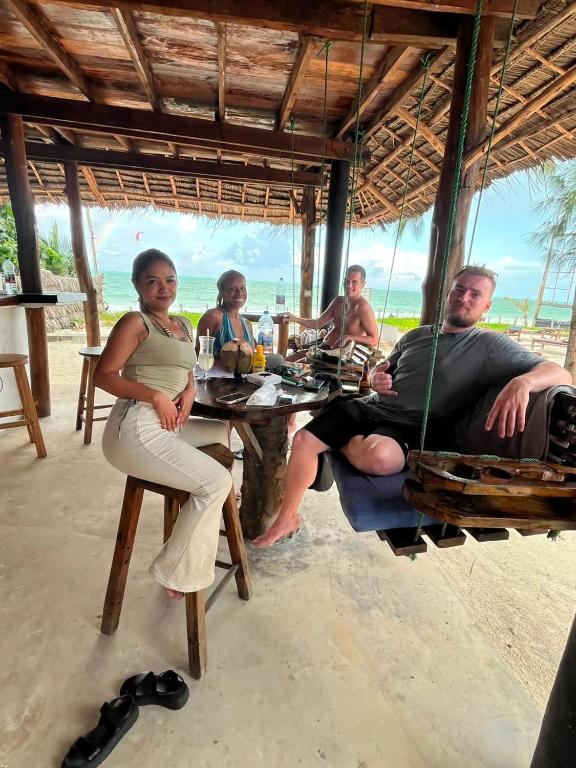 a group of people sitting at a table on the beach at Drifters Zanzibar in Paje