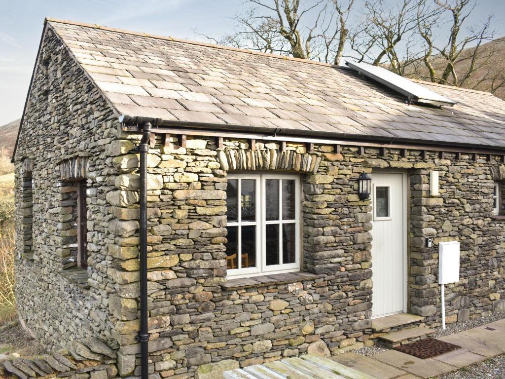 a small stone building with a white door at River View Cottage-Uk42226 in Low Borrowbridge