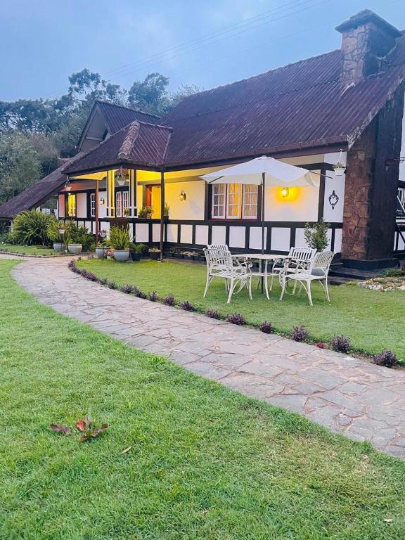 a house with two white chairs in front of it at The Cottage - Assure your Tickets for the Ella train journey in Ambawela