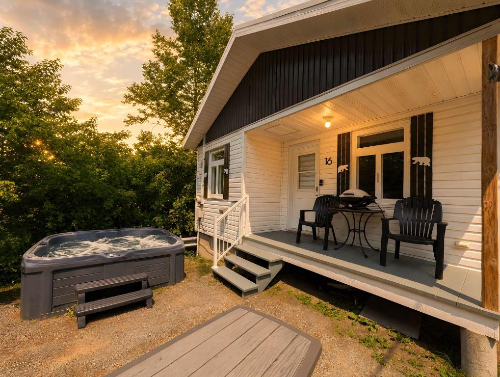 a porch with a hot tub and a table and chairs at Chic Shack with spa - near Massif Charlevoix & MSA in Saint-Tite-des-Caps
