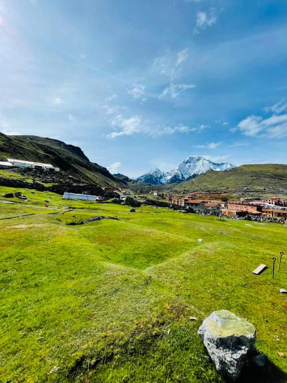 a field of green grass with mountains in the background at Hospedaje Vista Ausangate in Labramarca