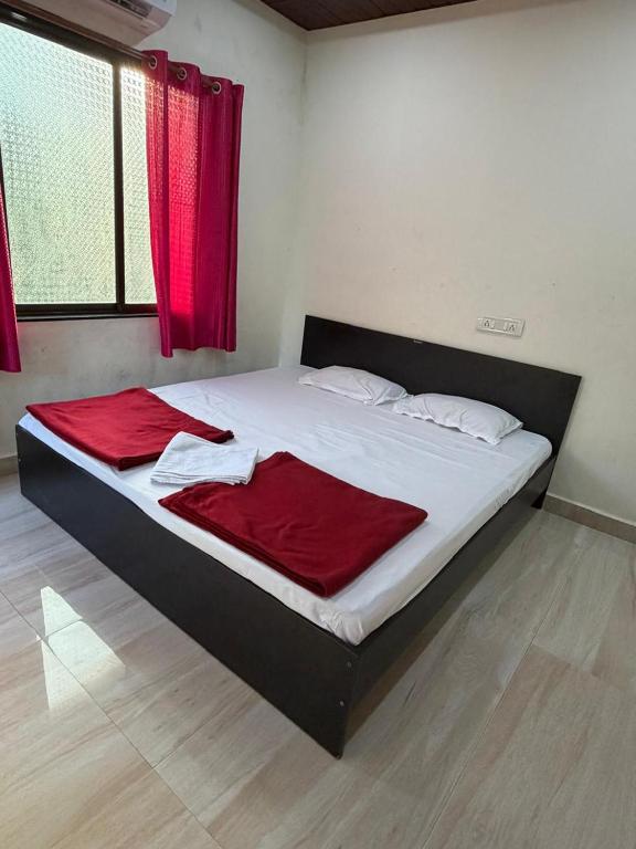 a bed in a room with a red blanket on it at Serina Guest House Malvan in Malvan