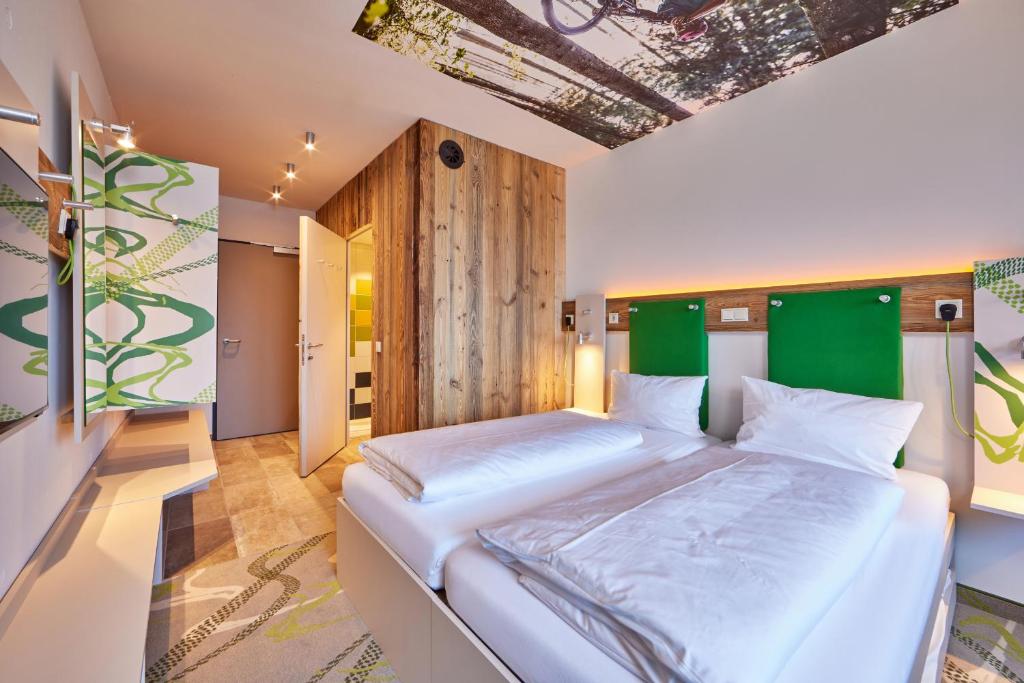 a bedroom with a large white bed with a green headboard at Explorer Hotel Bayrischzell in Bayrischzell