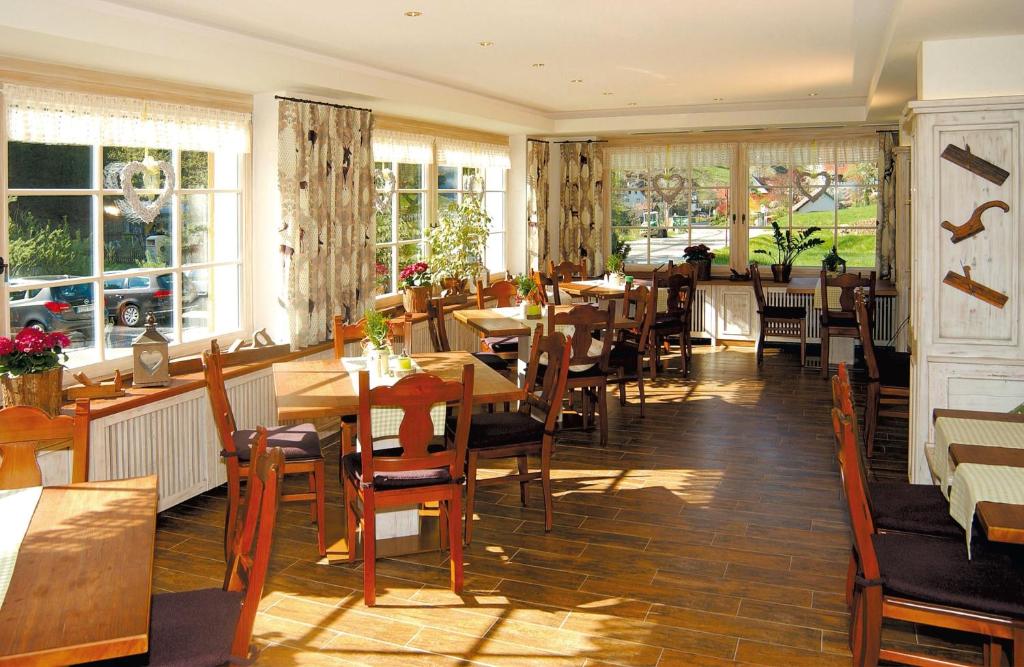 un restaurante con mesas y sillas de madera y ventanas en Schwarzwaldhotel Klumpp en Baiersbronn