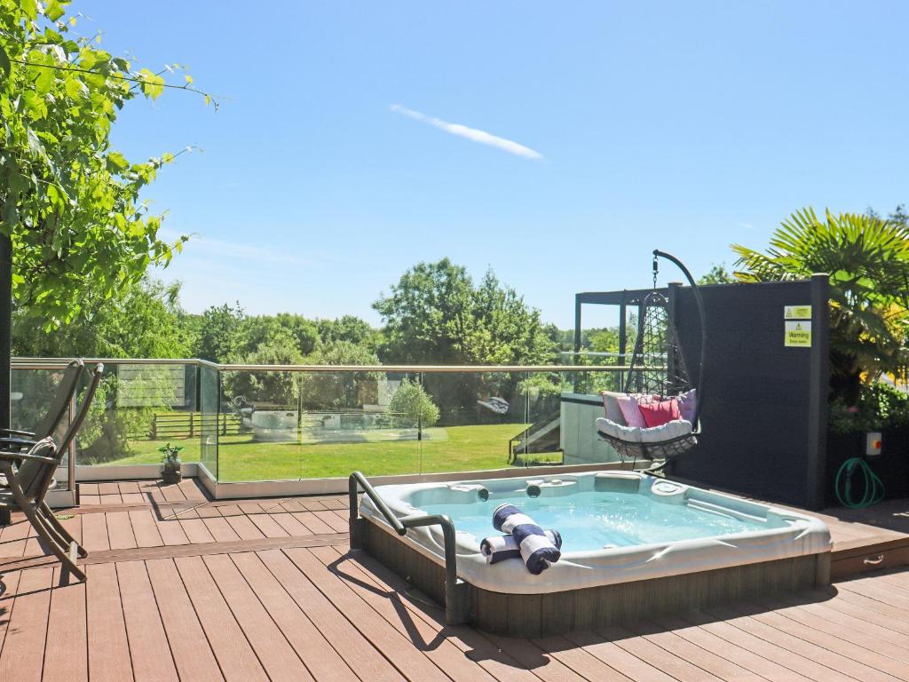 a hot tub sitting on a deck with a chair at Deerview Lodge - Uk51044 in Bonvilston